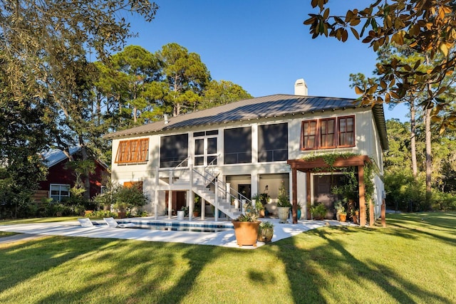 rear view of property with metal roof, a patio, a yard, stairway, and a chimney