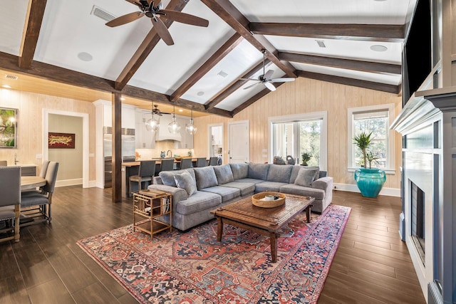 living area with vaulted ceiling with beams, a fireplace, dark wood-style floors, and visible vents