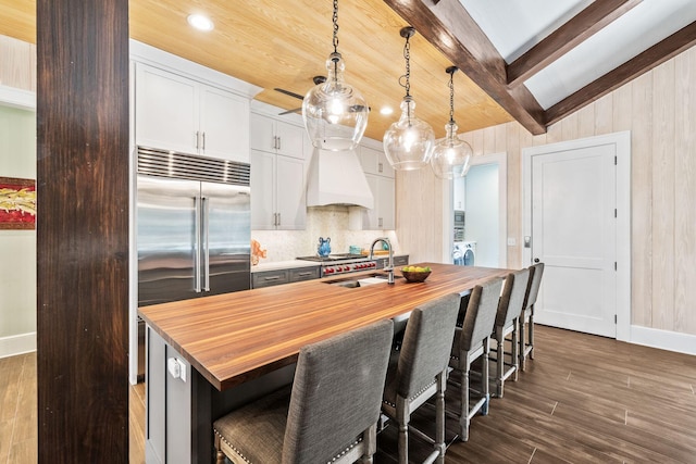 kitchen featuring dark wood-style floors, a sink, custom exhaust hood, wooden counters, and beam ceiling