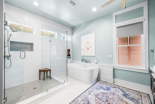 full bathroom featuring visible vents, ceiling fan, a shower stall, a freestanding tub, and baseboards