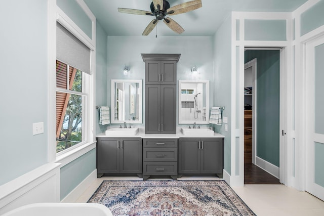 full bathroom with double vanity, ceiling fan, baseboards, and a sink