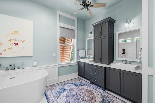 bathroom with double vanity, a healthy amount of sunlight, a freestanding bath, and a sink