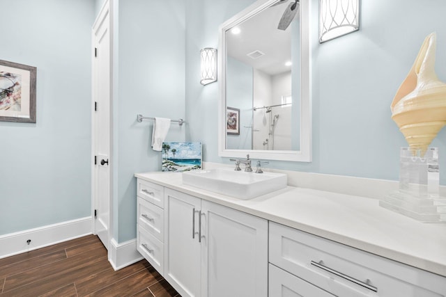 bathroom with visible vents, baseboards, wood finished floors, walk in shower, and vanity