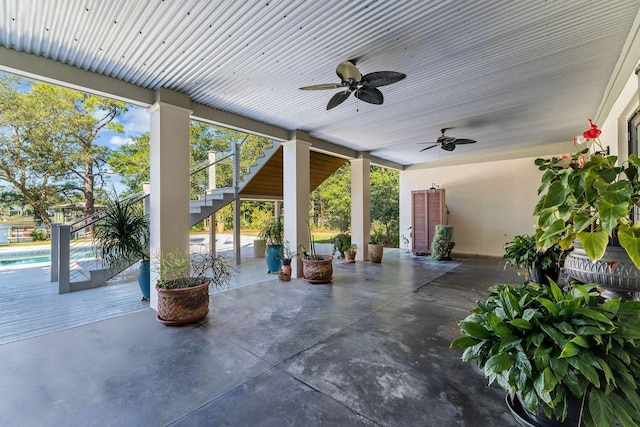 view of patio / terrace featuring stairway, a ceiling fan, and an outdoor pool