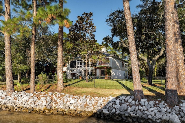 rear view of property featuring a water view, a fenced front yard, stairs, and a yard