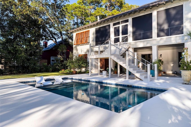 back of house with an outdoor pool, a sunroom, a patio, and stairs