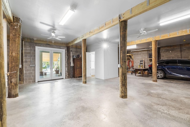 parking garage with concrete block wall, ceiling fan, and french doors