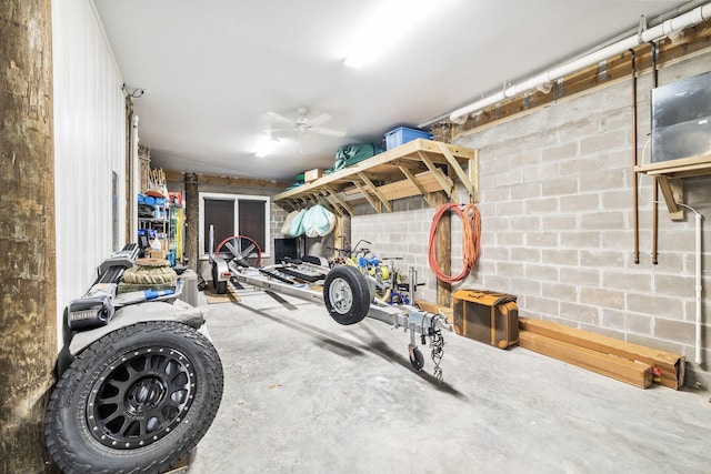 exercise room featuring a garage, concrete block wall, and a ceiling fan