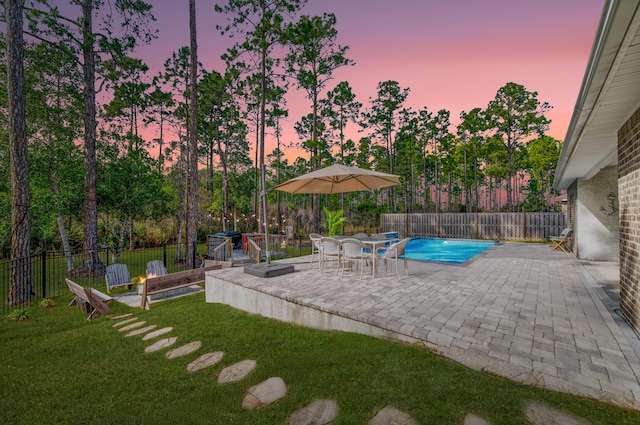 pool at dusk featuring a yard and a patio area