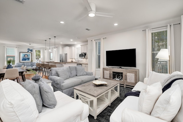 living room with crown molding, dark hardwood / wood-style floors, and ceiling fan