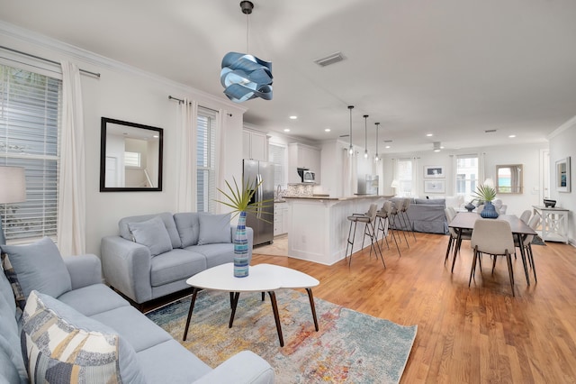 living room with ornamental molding and light hardwood / wood-style flooring