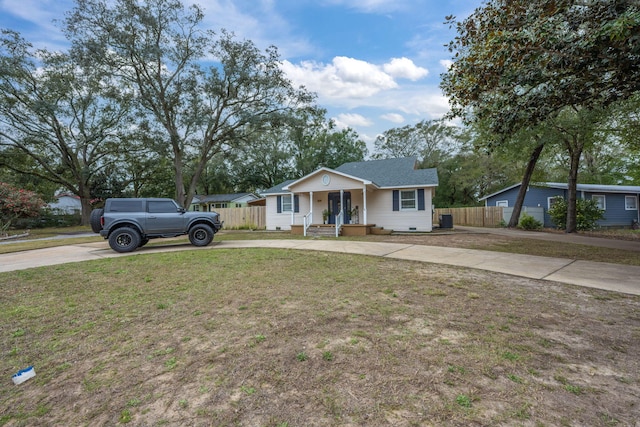 view of front of home with covered porch, concrete driveway, a front lawn, and fence