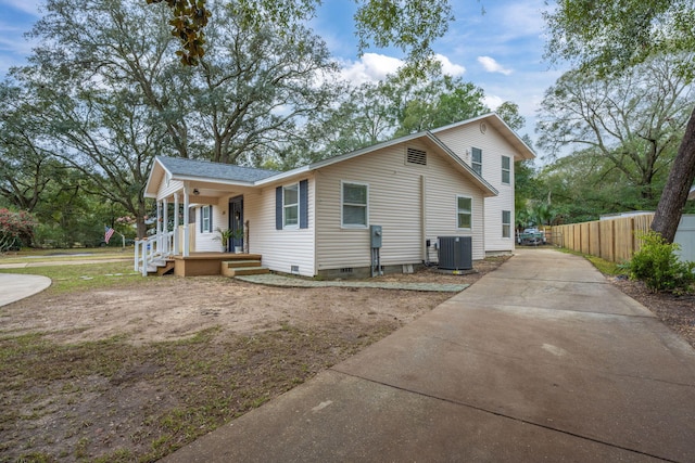 view of front of property featuring a porch, cooling unit, fence, driveway, and crawl space