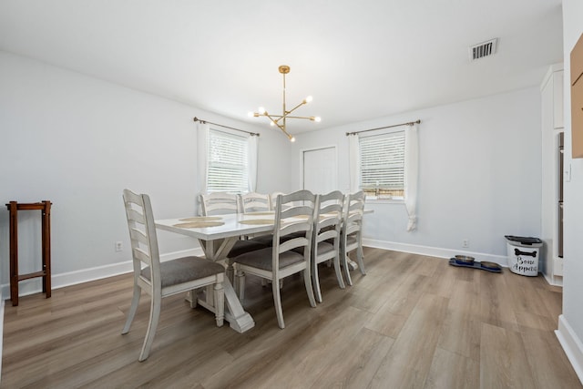 dining room featuring baseboards, light wood-style flooring, visible vents, and a notable chandelier