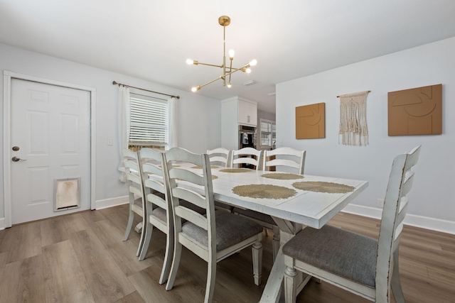 dining area featuring a chandelier, wood finished floors, and baseboards