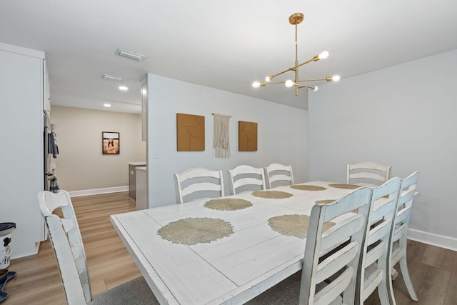 dining space featuring a notable chandelier, wood finished floors, visible vents, and baseboards