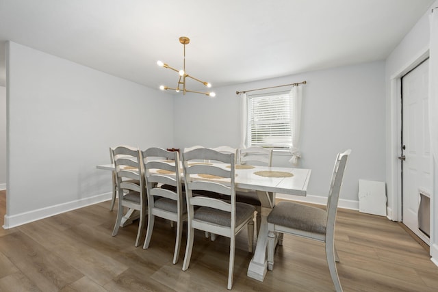 dining space with a chandelier, baseboards, and wood finished floors