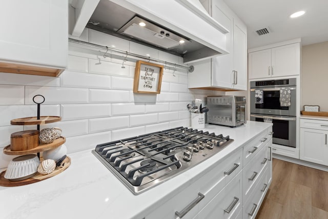 kitchen featuring custom exhaust hood, visible vents, appliances with stainless steel finishes, and light countertops