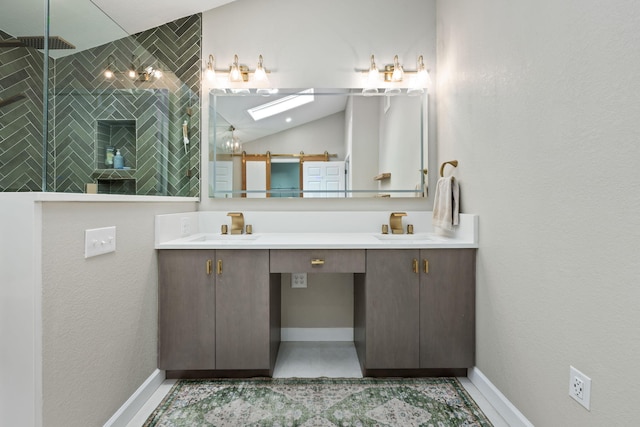 full bath featuring double vanity, baseboards, tiled shower, vaulted ceiling, and a sink