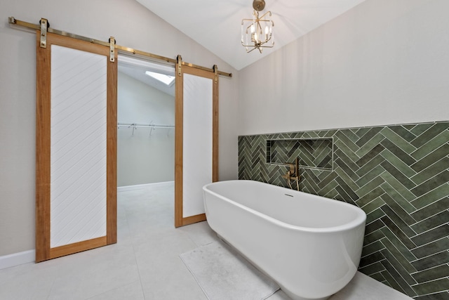 bathroom with lofted ceiling, tile walls, a soaking tub, tile patterned floors, and a walk in closet