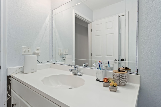 bathroom with a textured wall and vanity