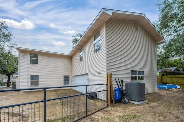 view of side of home with central AC unit, an attached garage, and fence