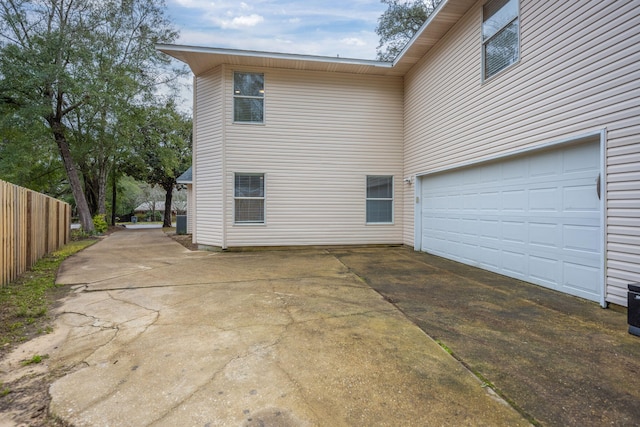 exterior space featuring a garage, concrete driveway, and fence