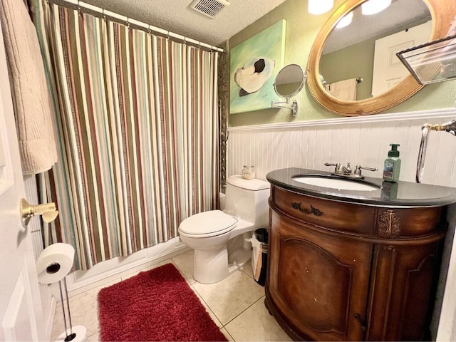 full bathroom featuring tile patterned floors, toilet, a textured ceiling, vanity, and shower / bath combo with shower curtain