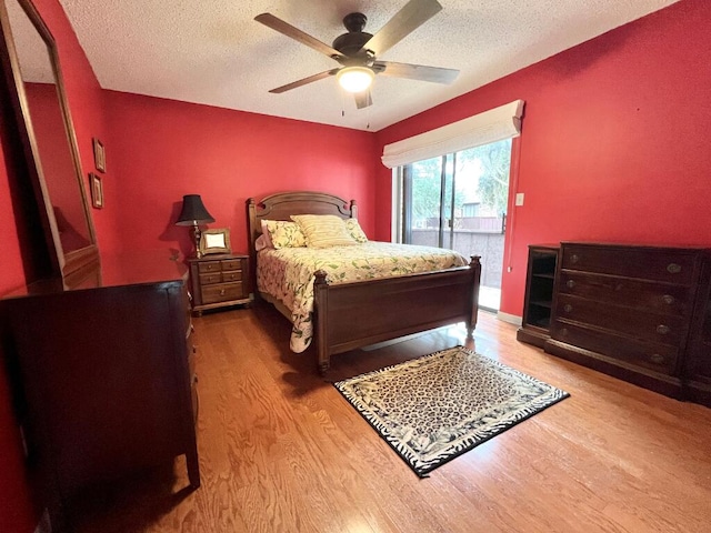 bedroom with ceiling fan, a textured ceiling, access to outside, and wood-type flooring