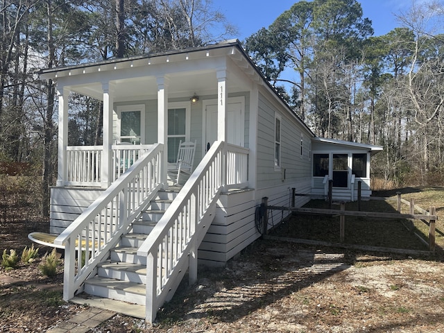 exterior space with stairs, a porch, and a sunroom