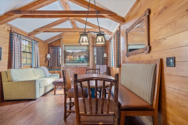 dining area with vaulted ceiling with beams, wood walls, and wood finished floors