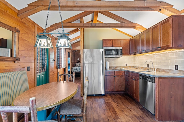 kitchen featuring dark wood-style flooring, decorative light fixtures, stainless steel appliances, light countertops, and a sink