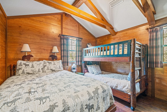 bedroom featuring vaulted ceiling with beams, dark wood-type flooring, wood walls, and visible vents