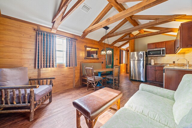 living area featuring lofted ceiling with beams, dark wood-type flooring, visible vents, and wooden walls