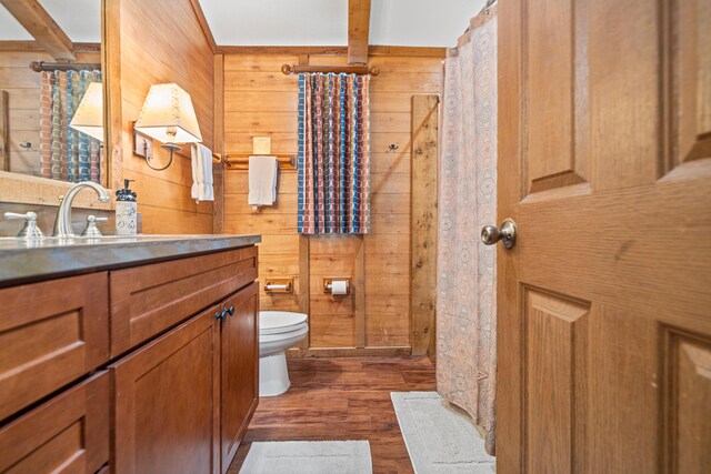 full bathroom featuring toilet, wood walls, wood finished floors, and vanity