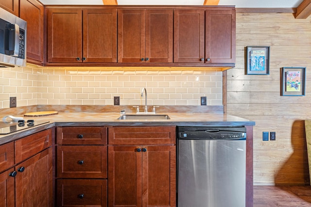 kitchen featuring brown cabinetry, decorative backsplash, wood finished floors, stainless steel appliances, and a sink