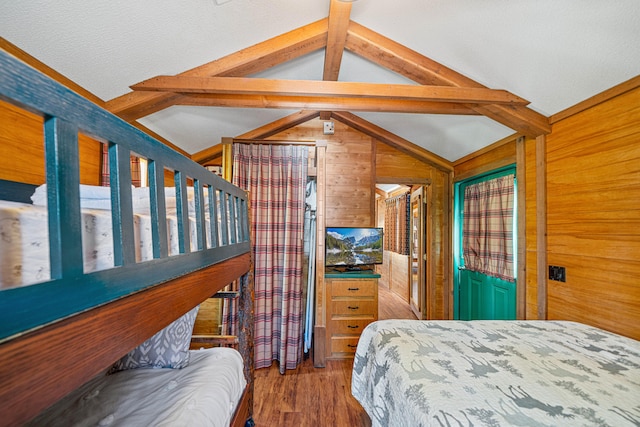 bedroom with vaulted ceiling with beams, wood walls, and wood finished floors