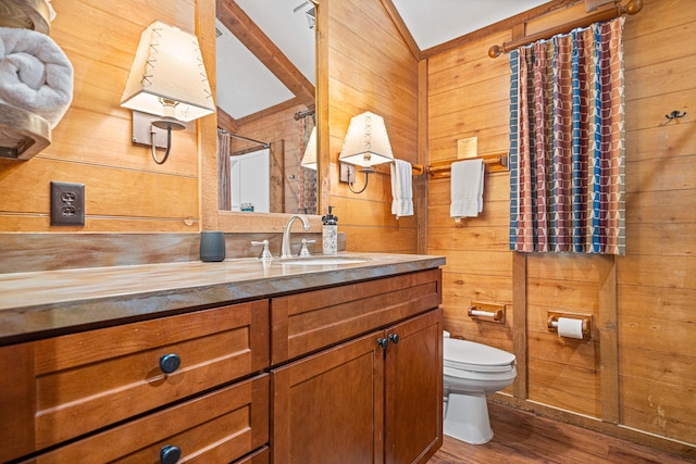 bathroom with toilet, a shower with curtain, wood finished floors, vanity, and wood walls