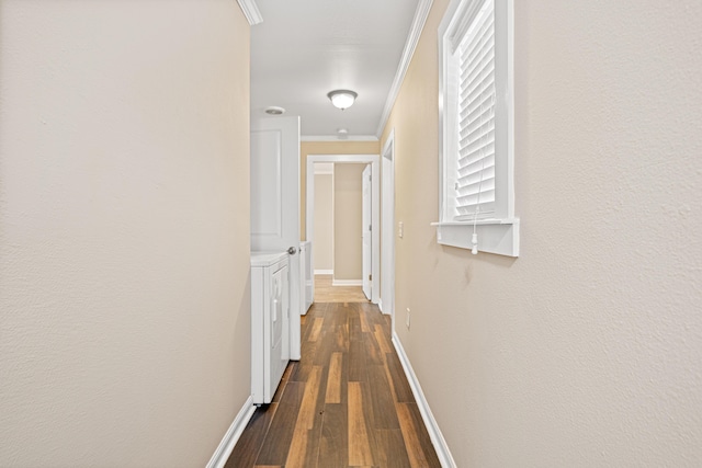 hallway featuring ornamental molding, dark wood-type flooring, washing machine and dryer, and baseboards