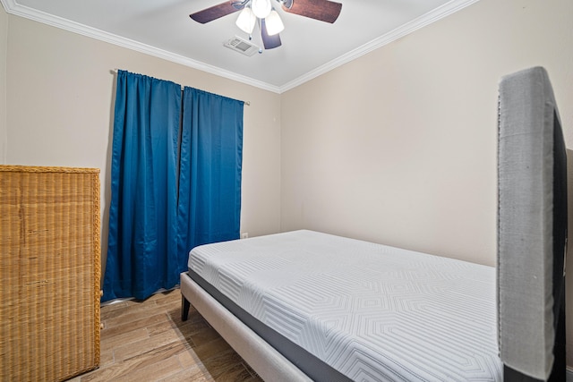 bedroom featuring a ceiling fan, light wood-type flooring, visible vents, and crown molding