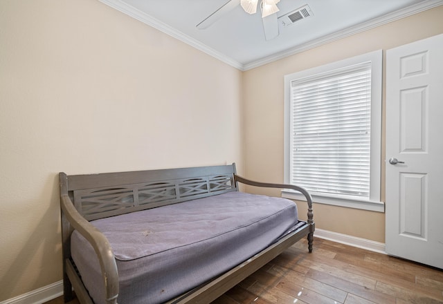 bedroom with visible vents, ornamental molding, a ceiling fan, wood finished floors, and baseboards