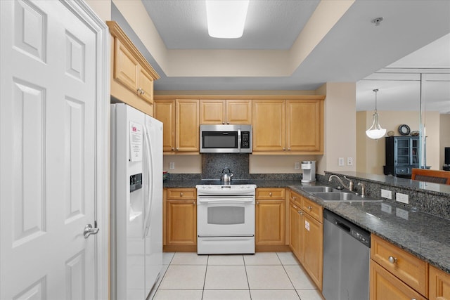 kitchen featuring sink, light tile patterned floors, appliances with stainless steel finishes, dark stone countertops, and hanging light fixtures