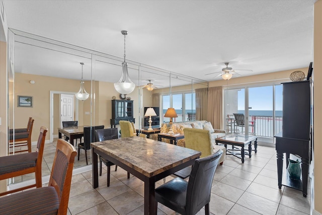 dining area featuring a water view, light tile patterned floors, and ceiling fan