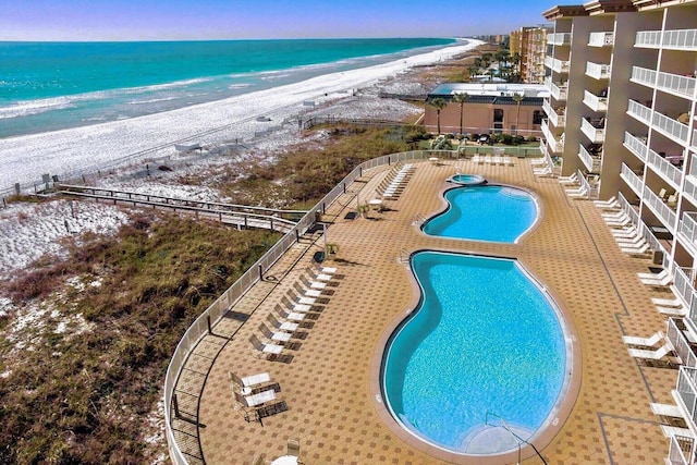 pool at dusk with a view of the beach, a patio area, and a water view