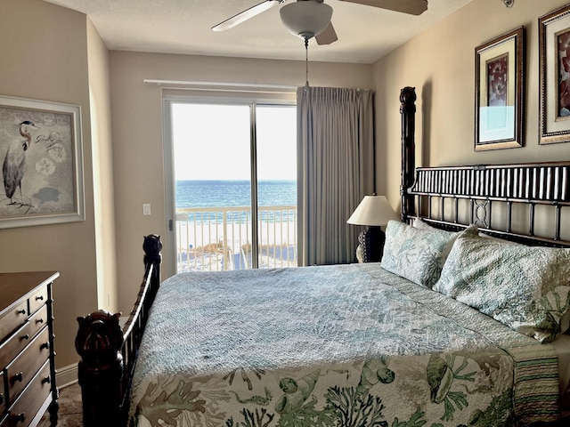 bedroom featuring a view of the beach, access to exterior, ceiling fan, and a water view