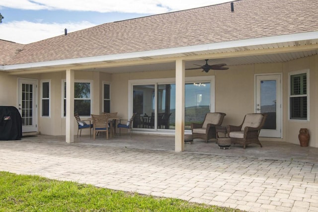 back of property with roof with shingles, a patio area, a ceiling fan, and stucco siding