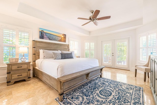 bedroom with access to exterior, ceiling fan, a raised ceiling, and french doors