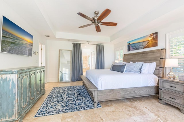 bedroom featuring a tray ceiling, multiple windows, and visible vents