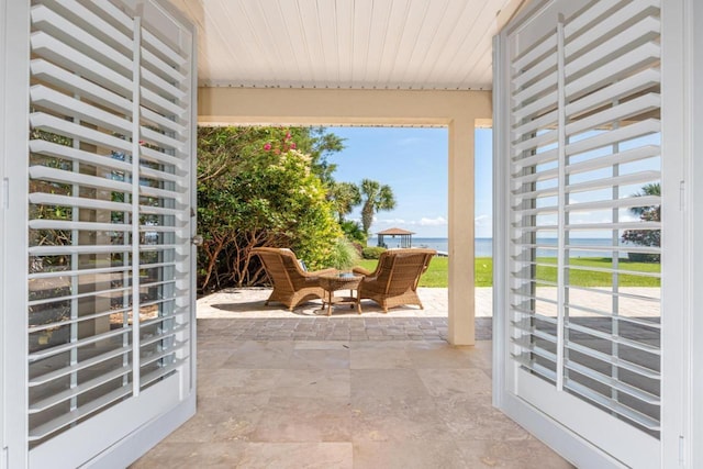 doorway to outside with a water view, wooden ceiling, and stone finish flooring