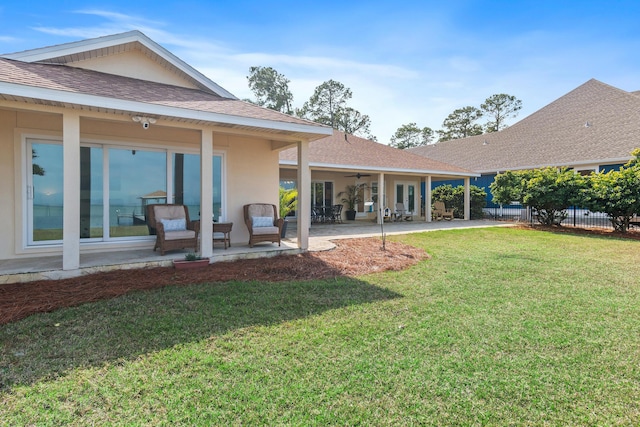 back of house with ceiling fan, roof with shingles, fence, a yard, and a patio area